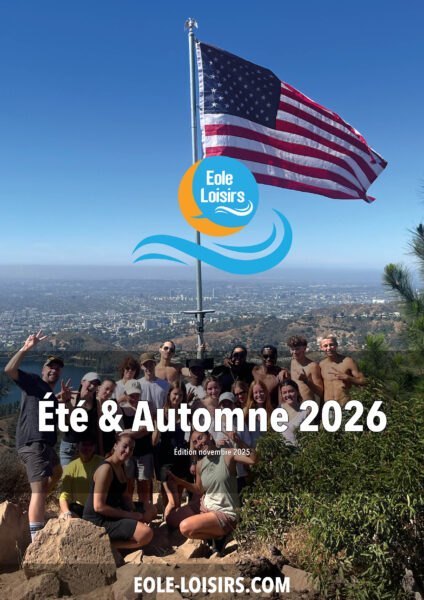 Groupe de personnes posant devant un drapeau américain sur une colline avec une vue panoramique.