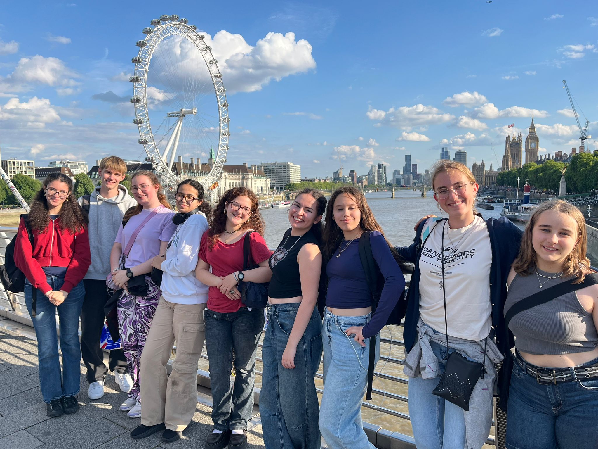 Groupe de jeunes adultes posant devant le London Eye et la Tamise à Londres, avec des bâtiments en arrière-plan.